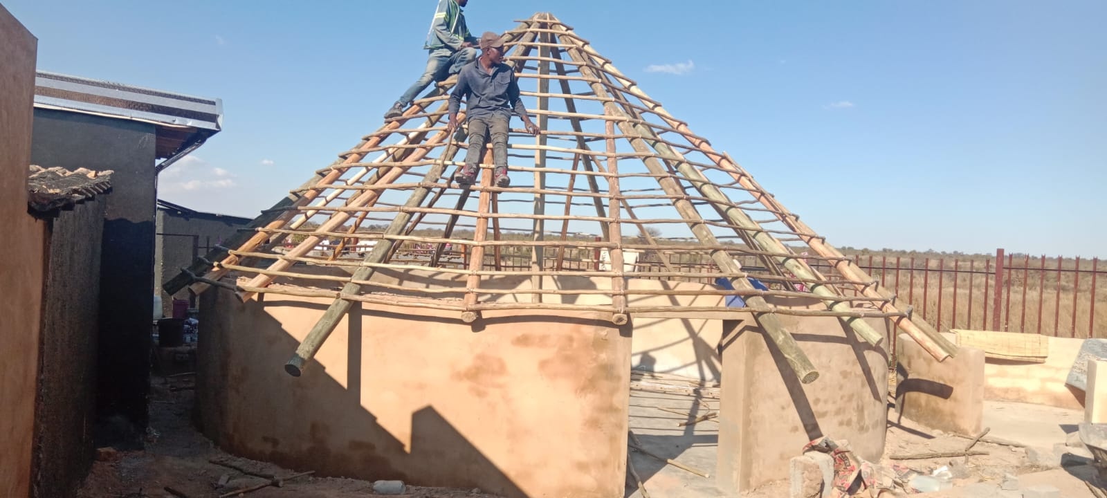 Timber pole roof framework being constructed on a round structure